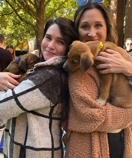 Two WalkWest employees holding a pair of dogs