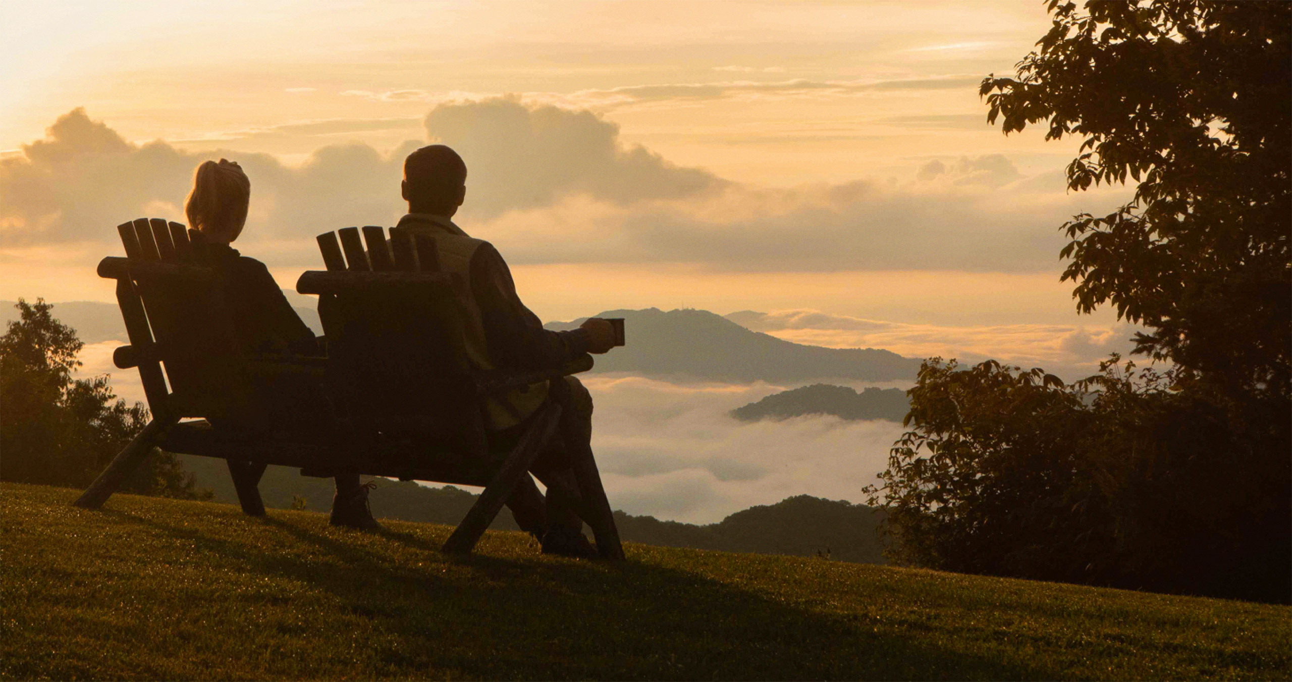 A couple seated on a mountain enjoying the view